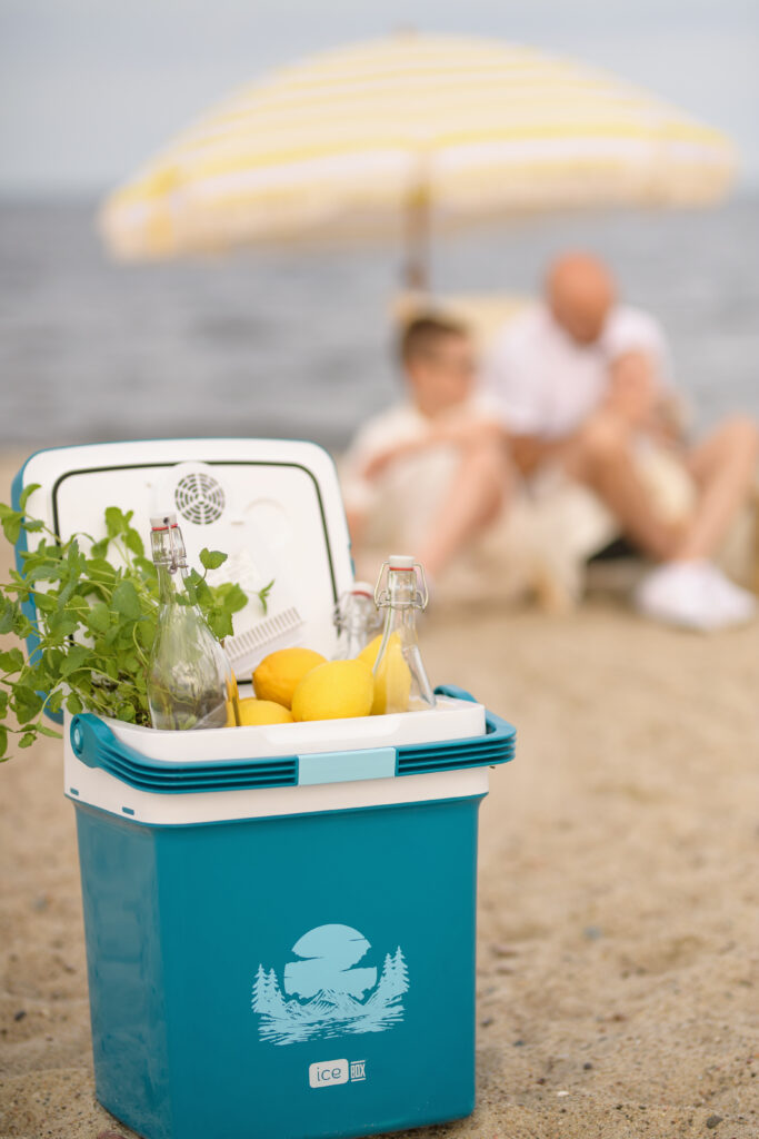 Lodówka turystyczna na plaży z cytrynami, miętą i butelkami z napojami